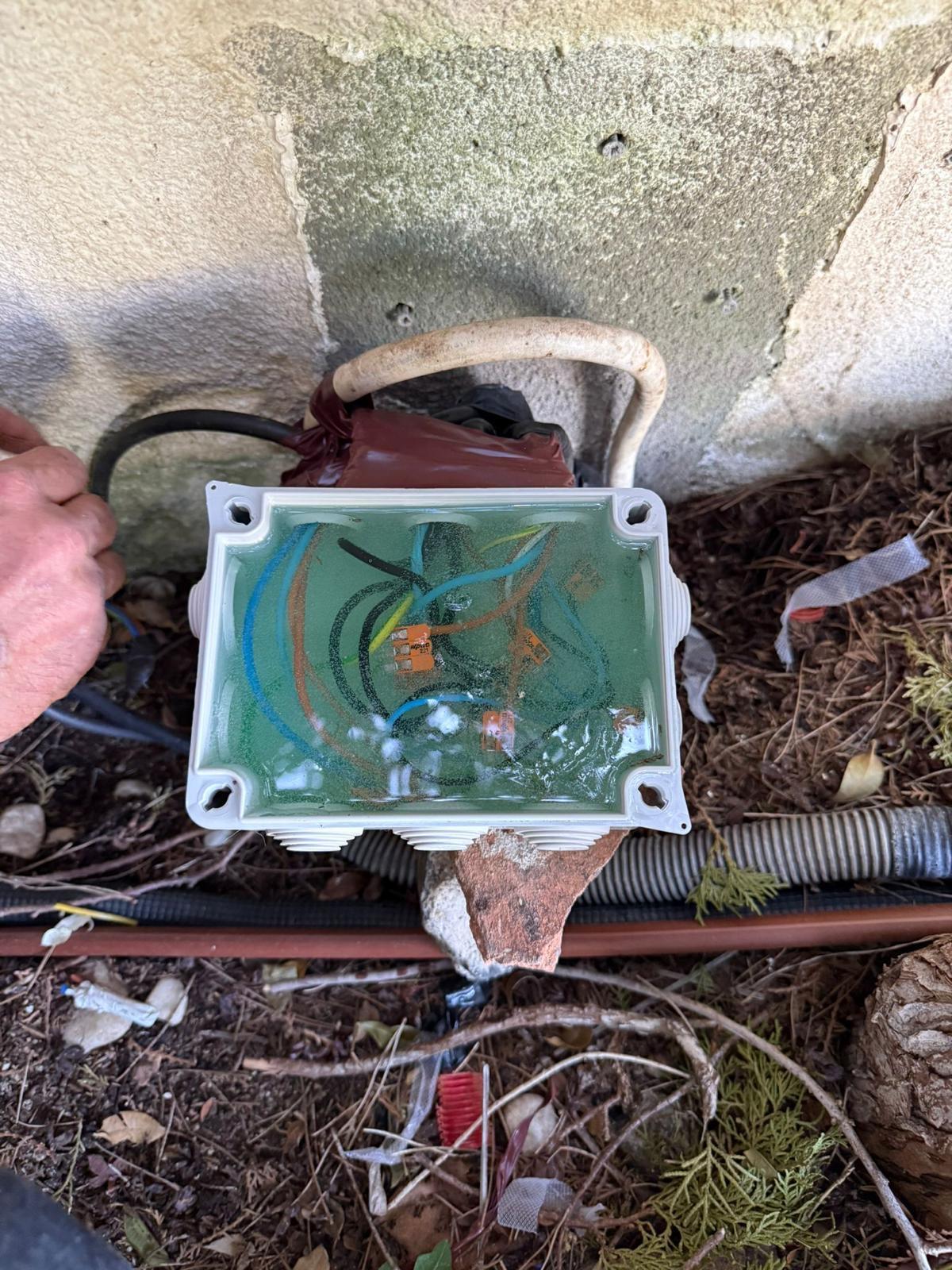 Caja de derivación exterior completamente llena de agua estancada, causa de una derivación eléctrica