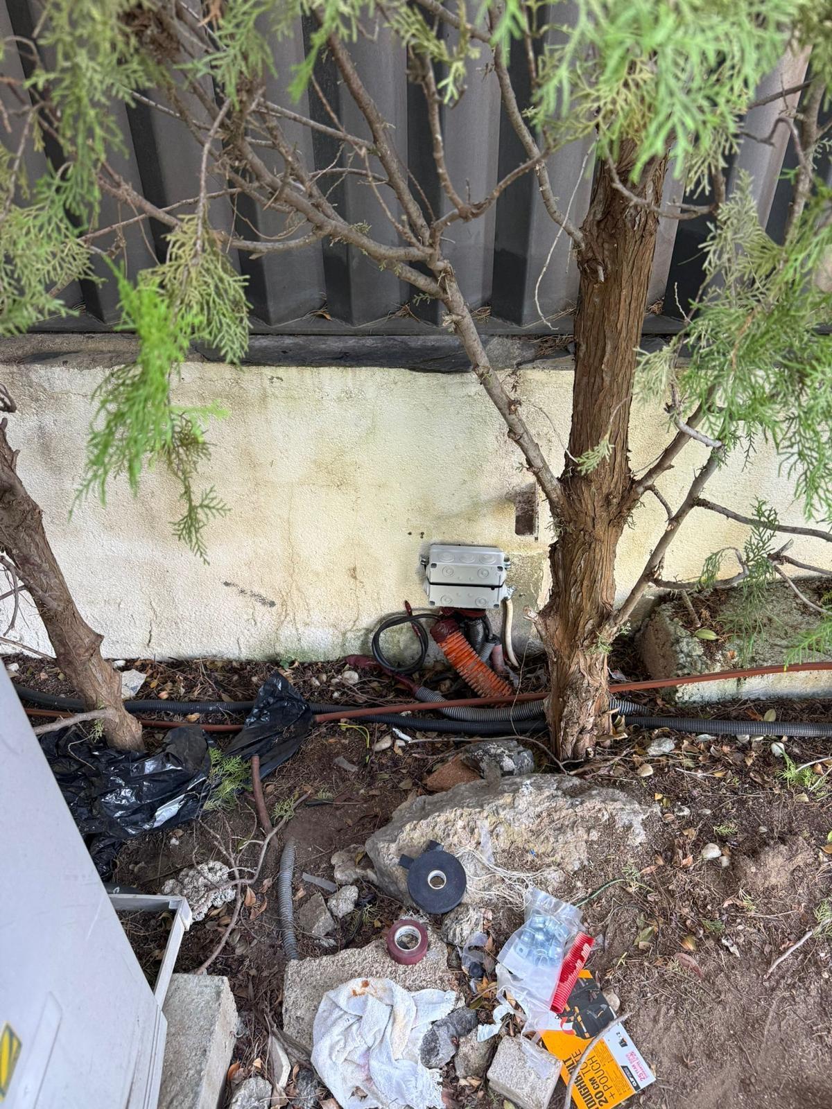 Caja de conexiones estanca instalada en el muro exterior de un jardín, con tubo corrugado y canalización enterrada