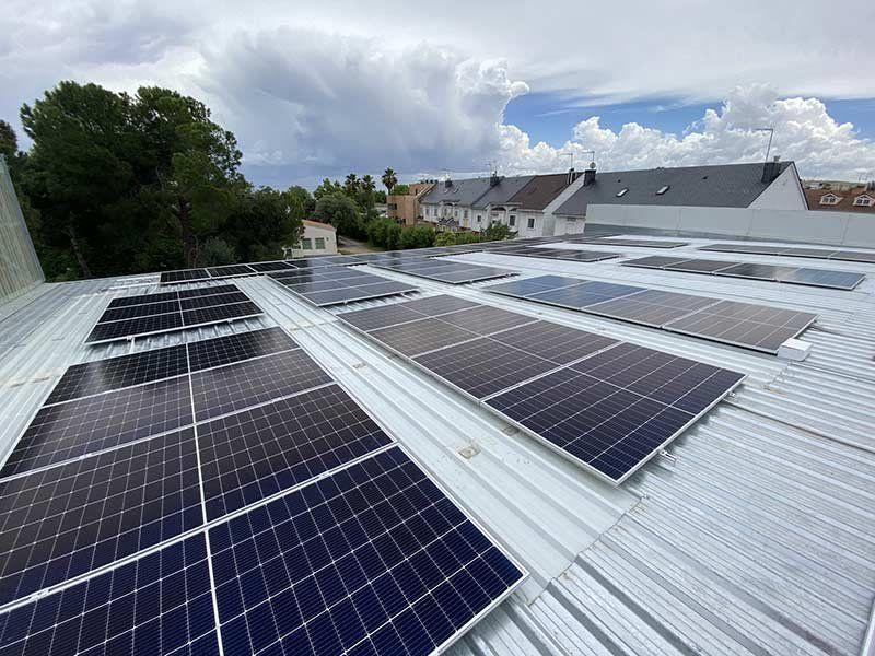 Placas solares fotovoltaicas montadas sobre una cubierta metálica en Castellar del Vallès, con nubes de tormenta al fondo